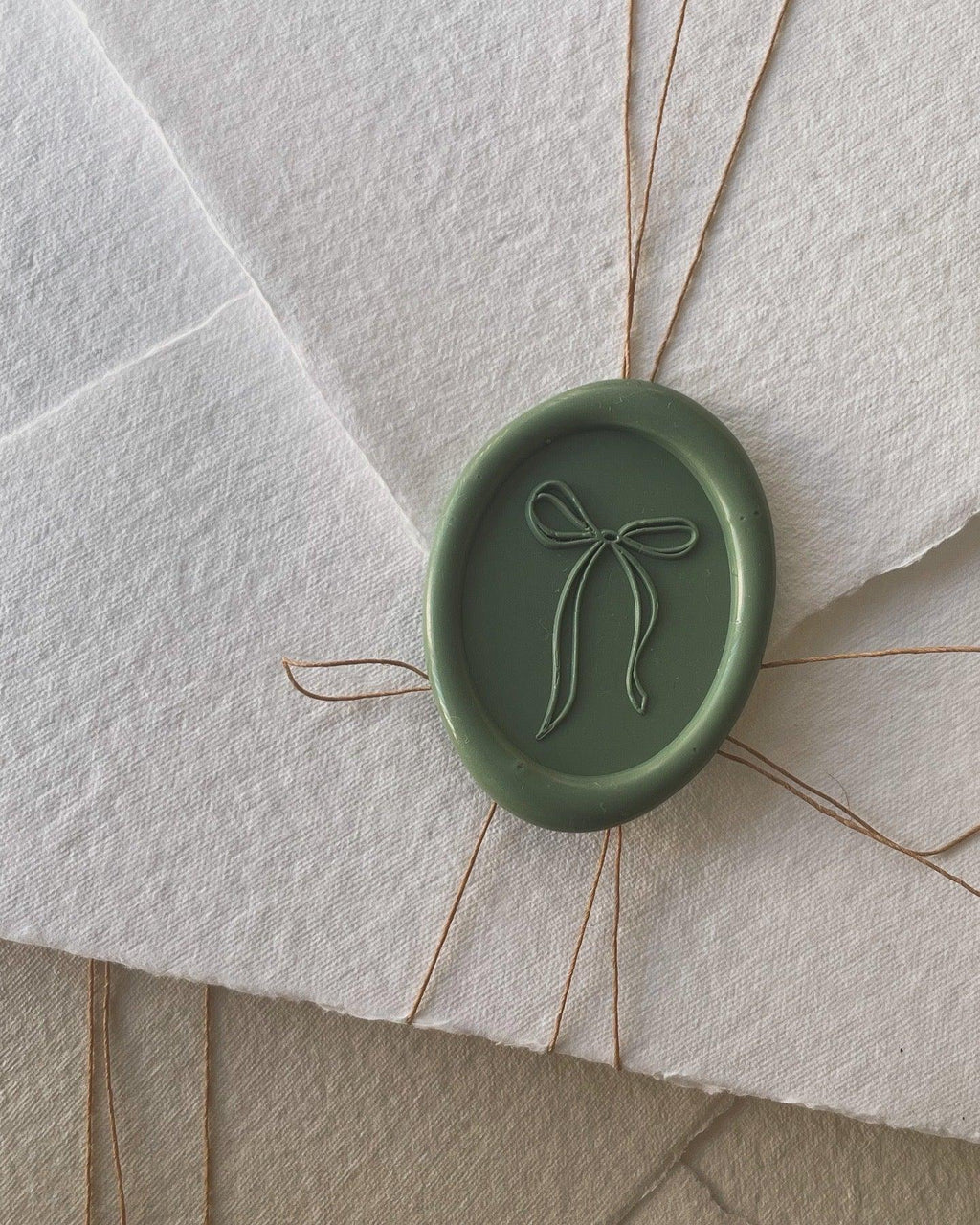 Green handmade wax seal with bow design for wedding invitations