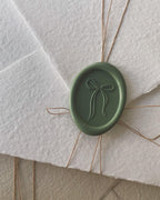 Green handmade wax seal with bow design for wedding invitations