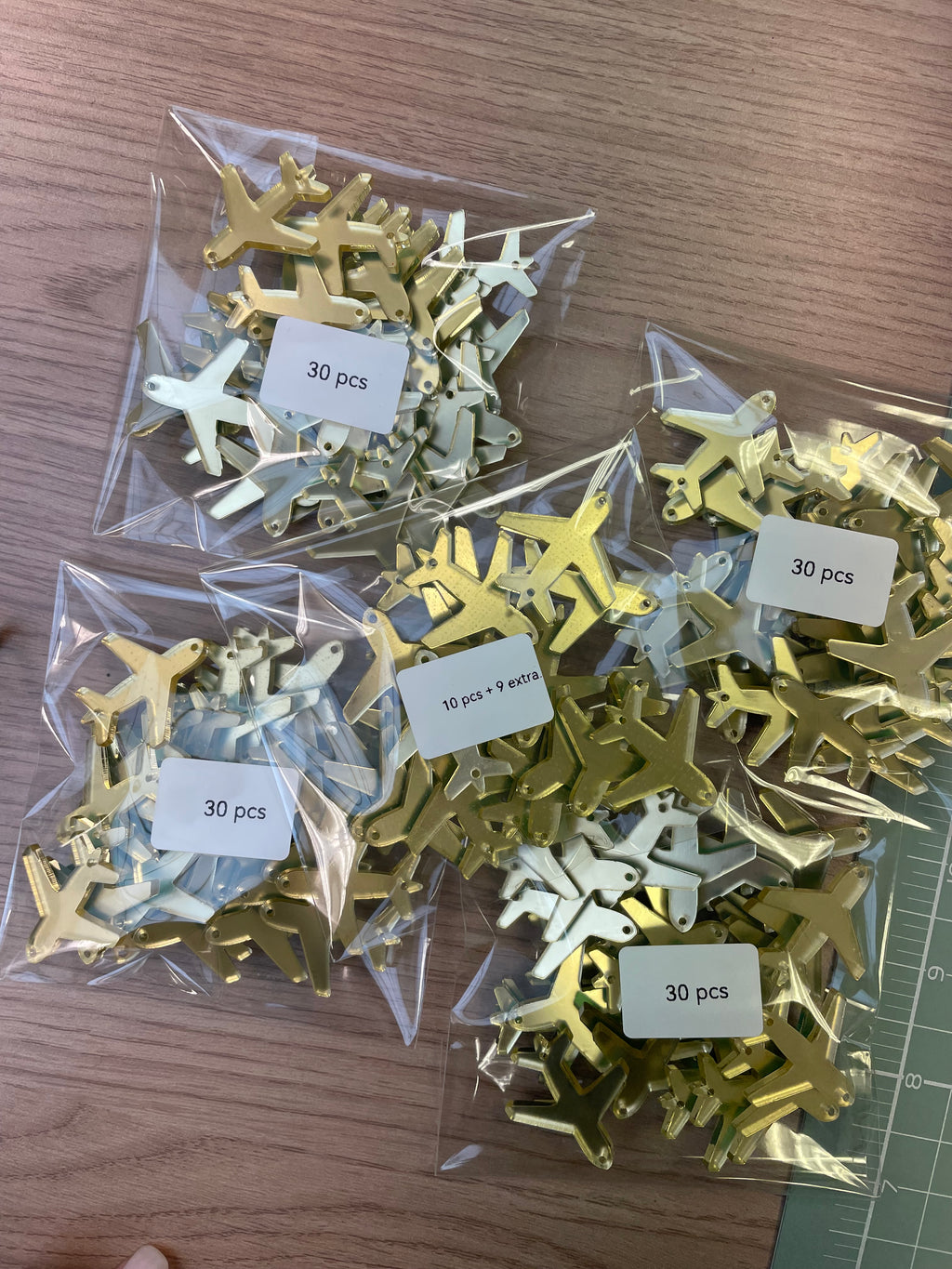 Gold and silver airplane charms for weddings in plastic bags