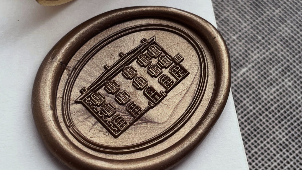 Bronze wax seal on a piece of paper with a textured surface in the background