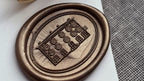 Bronze wax seal on a piece of paper with a textured surface in the background