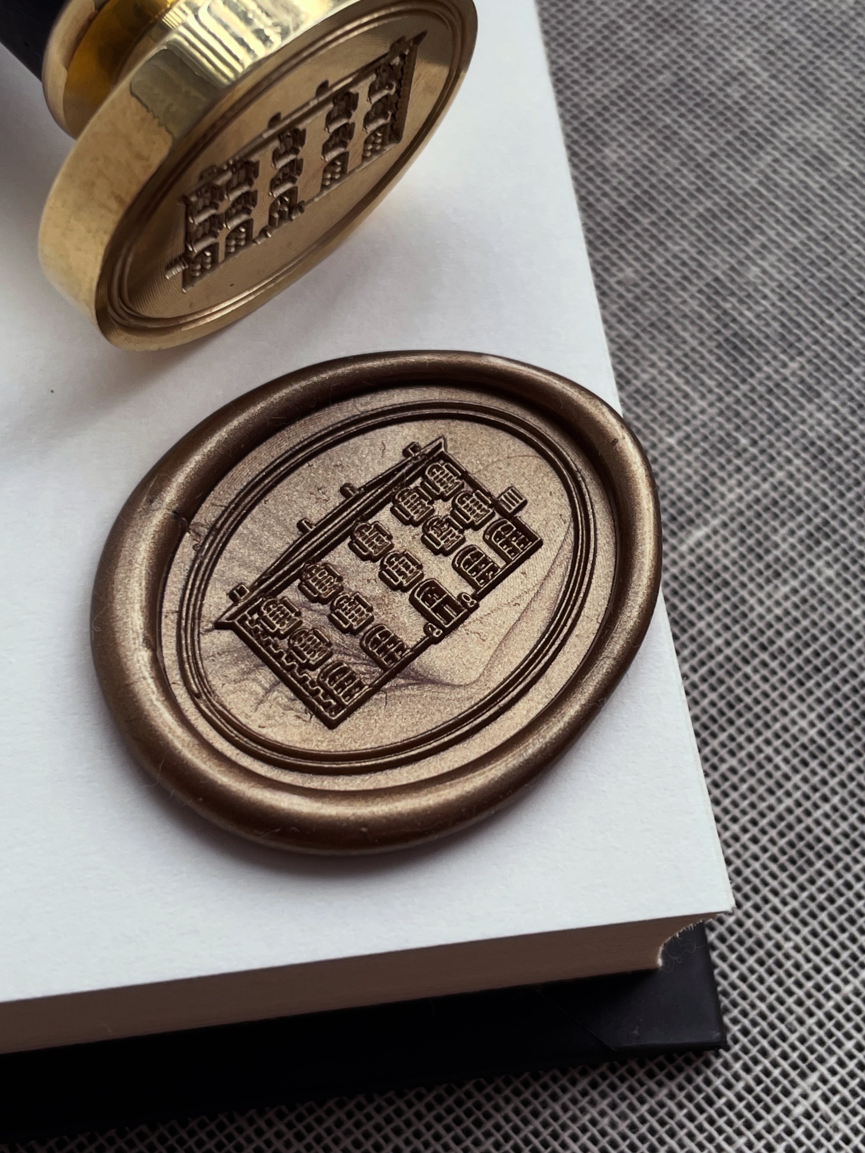 Bronze wax seal on a piece of paper with a textured surface in the background